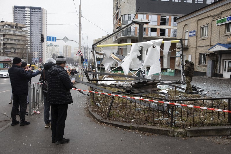 ウクライナの首都キエフで、ロシアの砲撃で破壊された建造物。そのそばではスマートフォンのカメラで人々が撮影していた＝2022年2月24日、AP