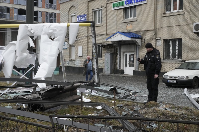 ウクライナの首都キエフで、ロシアによる砲撃の跡を撮影する警察官＝2022年2月24日、AP