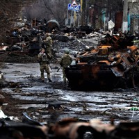 キーウ近郊で、破壊されたロシアの戦車や装甲車のそばで写真撮影するウクライナの兵士ら＝2022年4月2日、ロイター