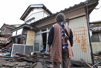 地震と津波で壊れた自宅前に立つ濱市正子さん。津波にさらわれたとみられる夫鉄次さんの安否は分かっていない＝石川県珠洲市宝立町鵜飼で2024年1月6日午前11時35分、山崎一輝撮影