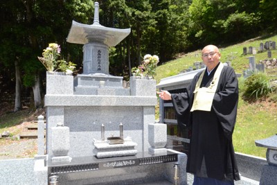 墓じまいした檀家や区外の人を合同でまつる佛名寺の合祀塔と森屋徹全住職＝京都府南丹市で2024年5月29日午前11時47分、宮城裕也撮影