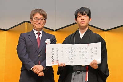 王位就位式で就位状を手にする藤井聡太王位。左は、日本将棋連盟の羽生善治会長＝東京都千代田区で2024年11月12日午後4時11分、新宮巳美撮影