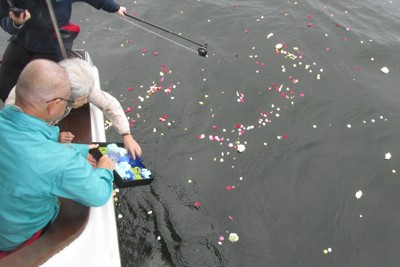 弘津優さんの遺骨を散骨後、花びらをまく両親＝東京湾で2024年10月9日午後1時50分、岡田英撮影