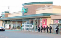 Police officers head into an Akita city supermarket on Dec. 2, 2024, to check a trap after a bear entered the store two days earlier. (Kyodo)