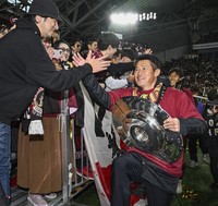 Vissel Kobe manager Takayuki Yoshida celebrates with a supporter while holding the championship silverware after the team successfully defended its J-League title with a 3-0 win over Shonan Bellmare at Noevir Stadium Kobe on Dec. 8, 2024. (Kyodo)