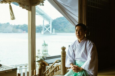 和布刈神社の神主、高瀬和信さん。社殿からは関門海峡にかかる関門橋が見える＝本人提供