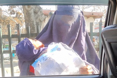 アフガニスタンのイスラム組織タリバンの復権後、子どもを抱きながら物乞いをする女性＝カブールで2021年12月4日、松井聡撮影