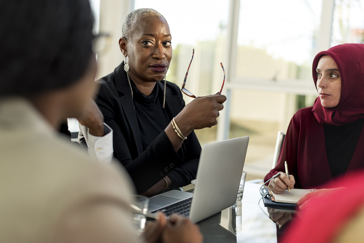 A middle-aged black woman professional leading a meeting with a multicultural and multiracial working group