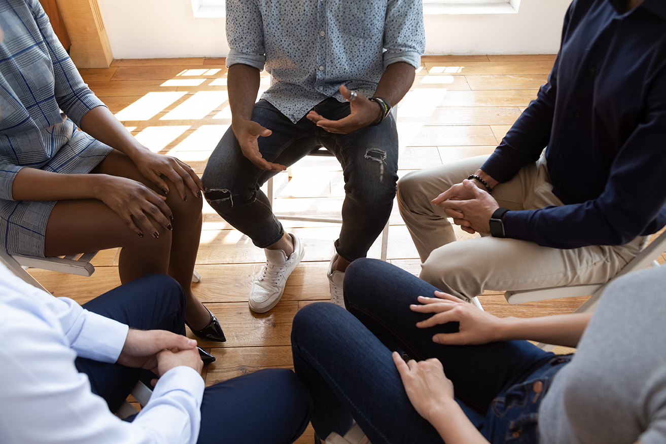 A diverse group of people seated in a circle, conducting a group discussion. 