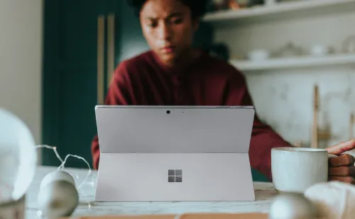 A staff member working at their desk on a Microsoft Surface Tablet