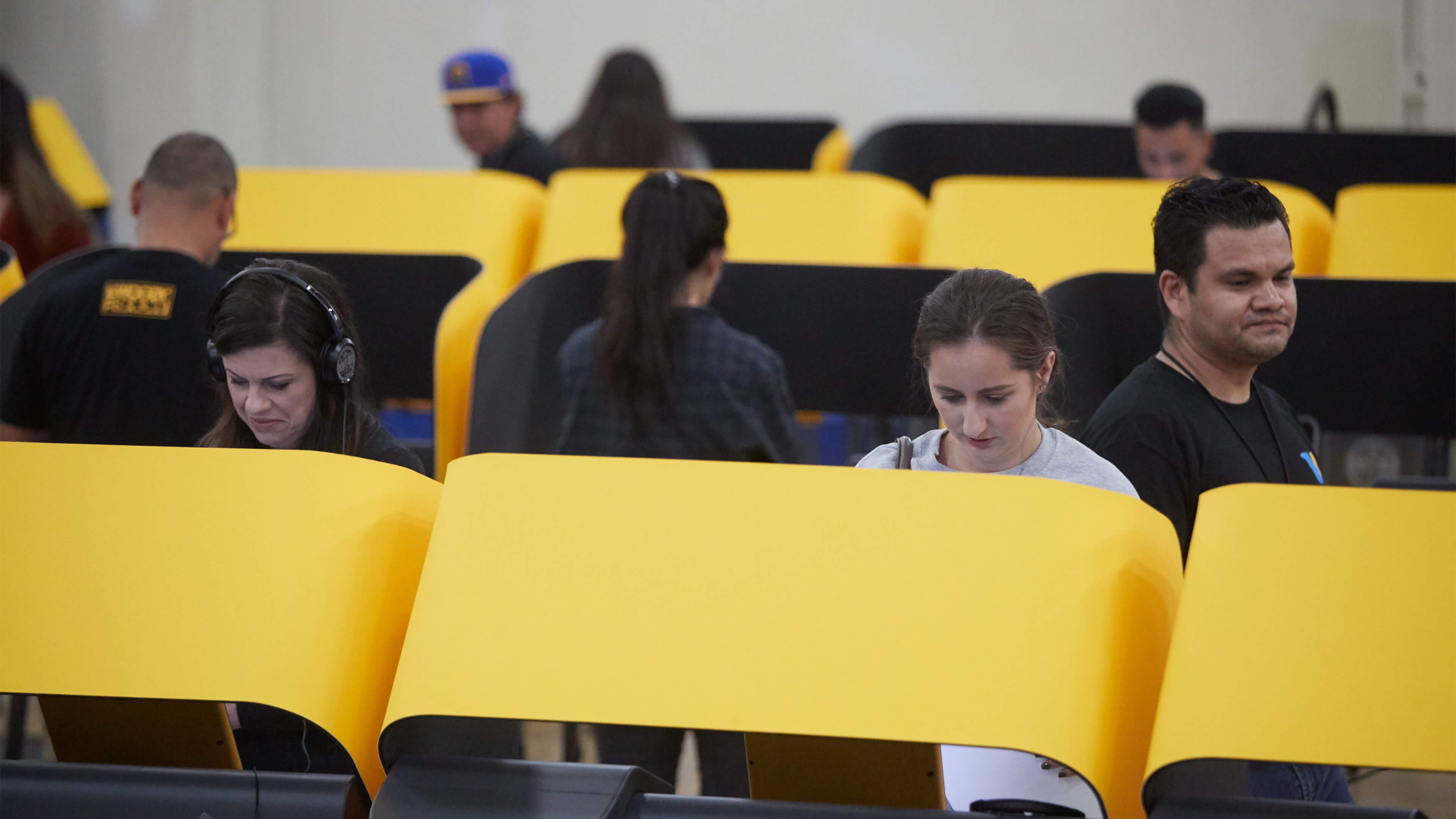 People standing at big yellow voting booths