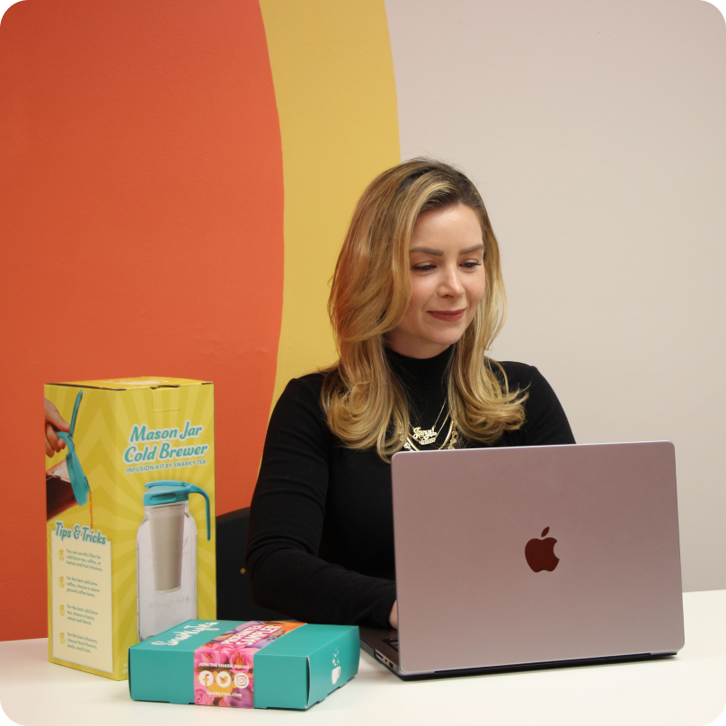 Jenni-Lyn Williams, CEO de SnarkyTea, trabajando en su computadora con productos SnarkyTea a su lado