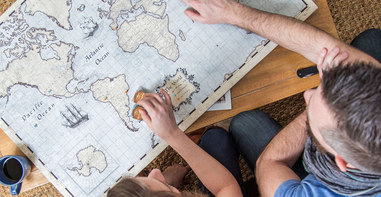 Overhead shot of two people looking at a world map on a coffee table