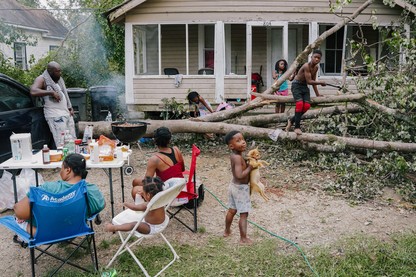 A famile prepares dinner in their front yard after Hurricane Ida.