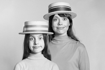 Mother and daughter pose with straw hats.