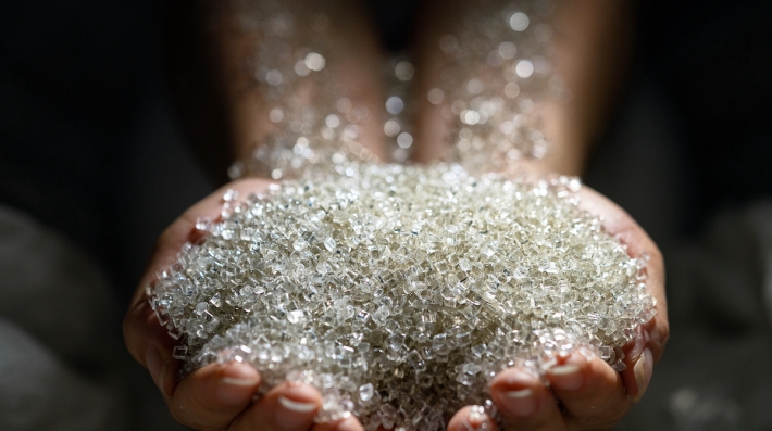 Uma pilha de pequenas bolinhas de plástico caindo em mãos estendidas.