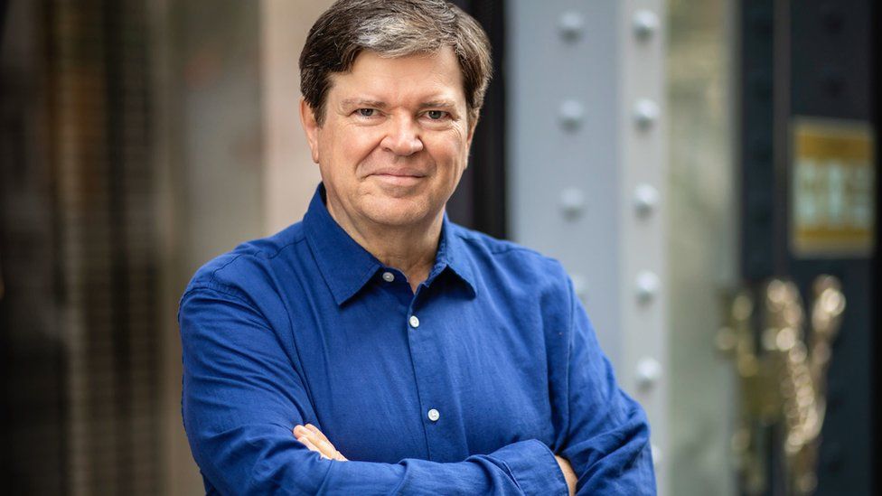 Yann LeCun crosses his arms in a blue shirt.