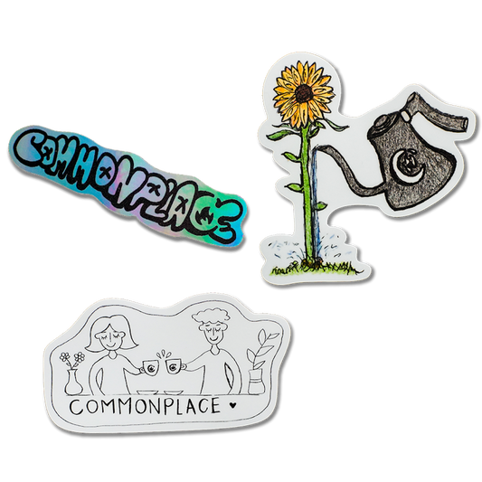 Three sticker designs. The first is the word "Commonplace" written in a graffiti font. The second is a scene with two friends "cheers"-ing their coffee mugs behind a counter with plants on it. The third is a coffee pour over kettle watering a sunflower. 