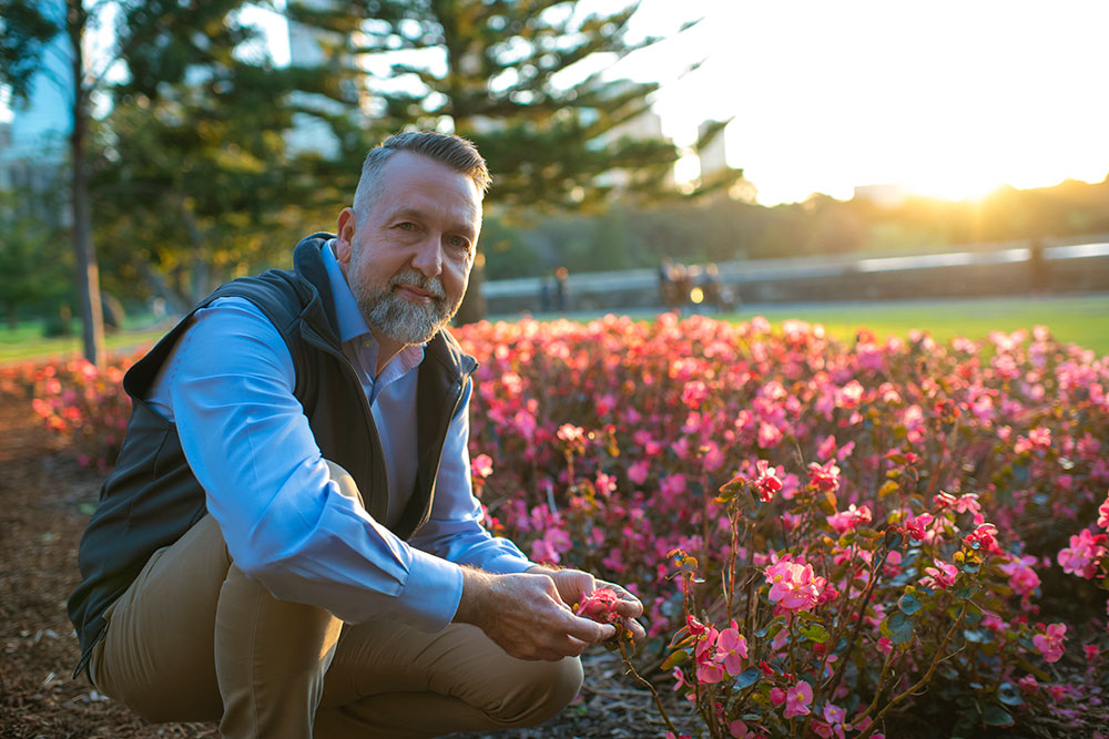 Jimmy L. Turner, new executive director of the Red Butte Garden, cradles some pink tulip-like flowers in golden light.