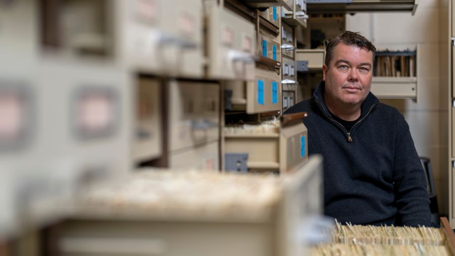 Mark sits behind an open filing cabinet, facing the camera