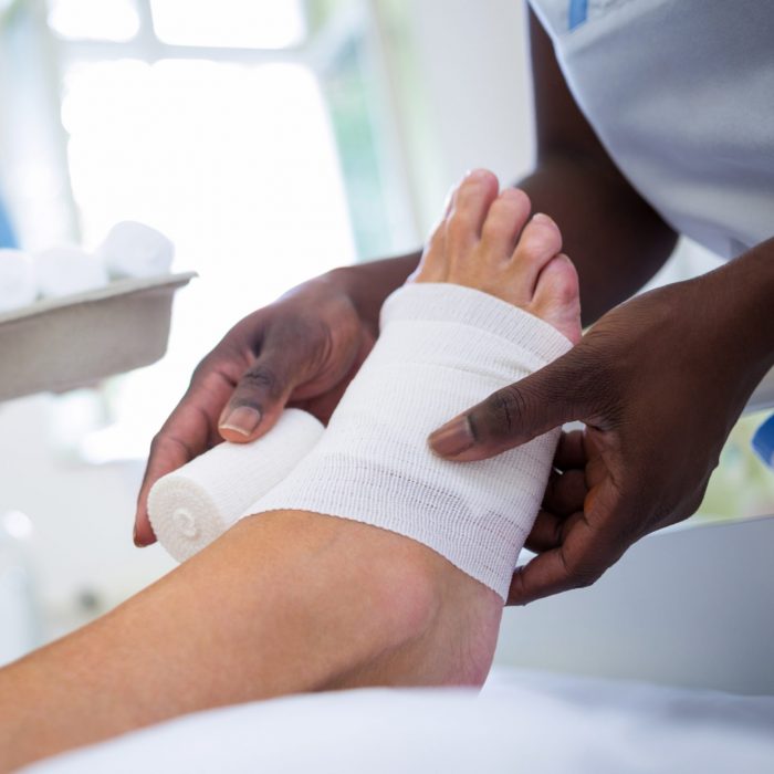 Doctor bandaging patients leg in hospital