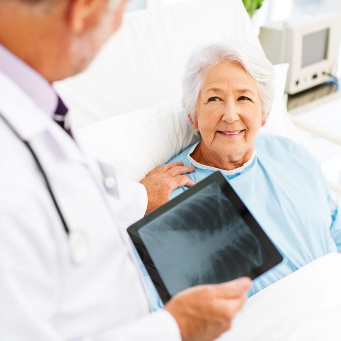 Woman Looking At Doctor With X-Ray On Digital Tablet