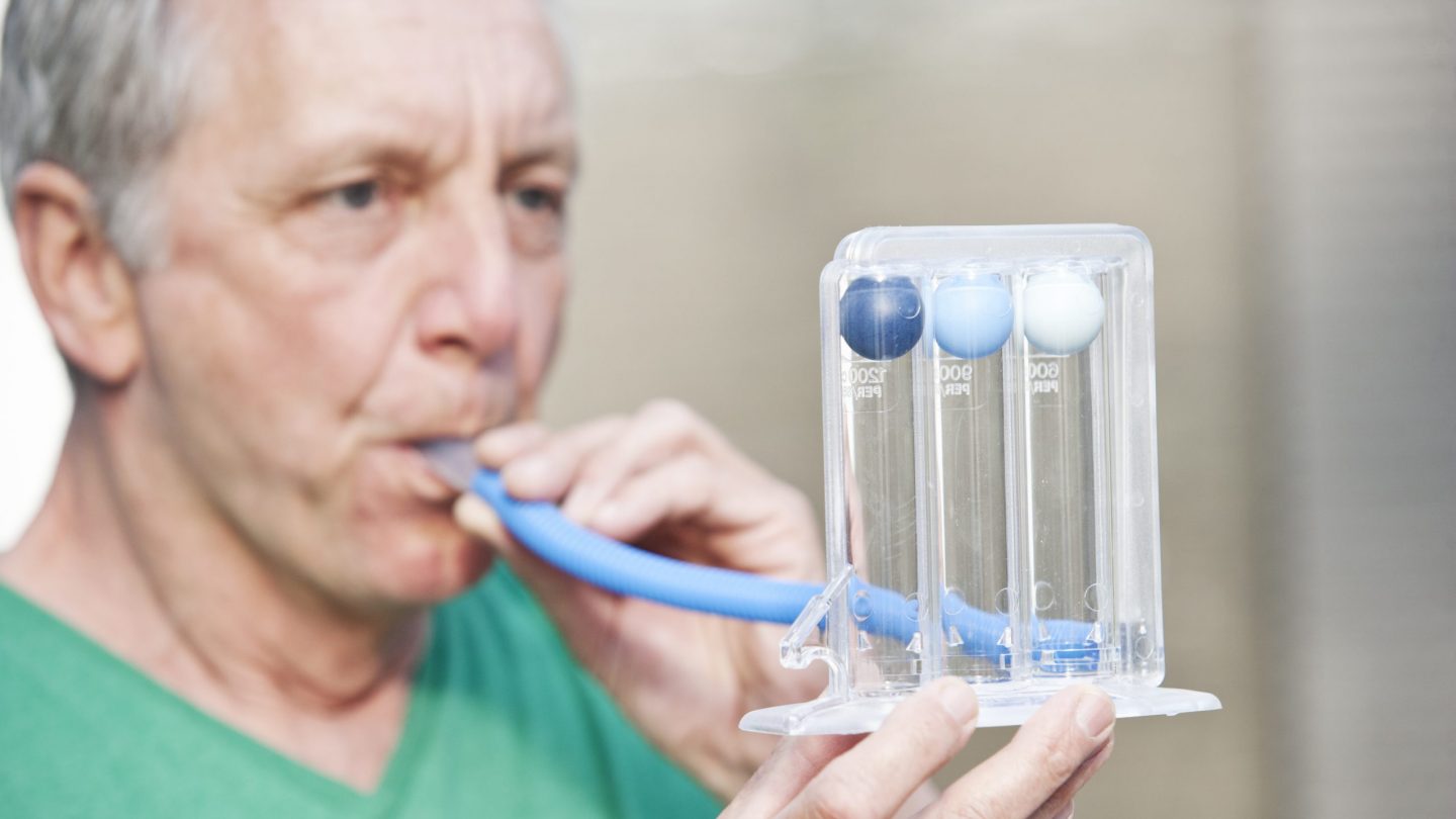 Male person performing lung function test by using a triflow