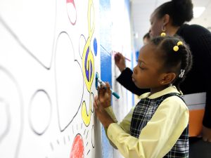 A child drawing on a whiteboard with a marker.