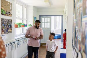 An adult and a child walking down a hallway.