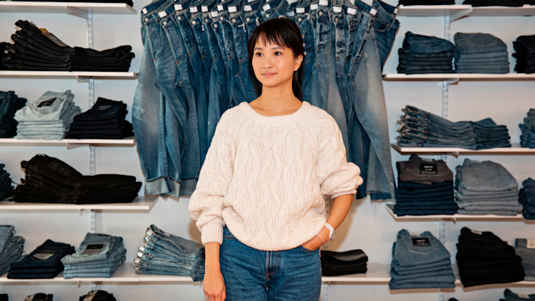 Co-owner of Azalea standing in front of a wall of merchandise.