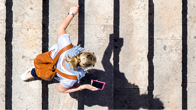 Aerial view of woman walking in city with phone in hand