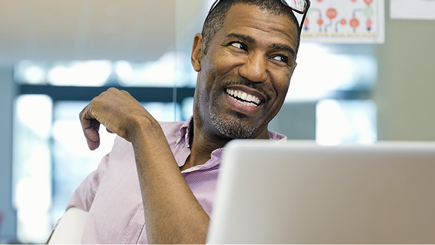 Happy professional man in office with laptop