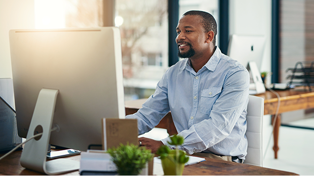 Small business owner man working at his desktop computer in a bright office space