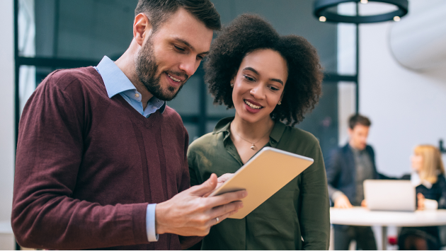 Two colleagues standing and looking at a tablet in office