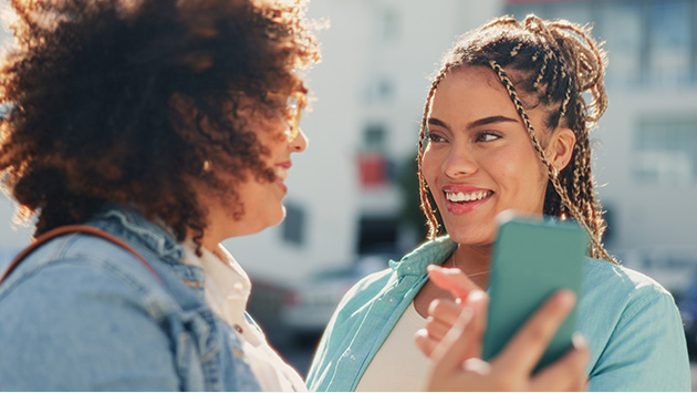 Two friends happily looking at one woman’s phone