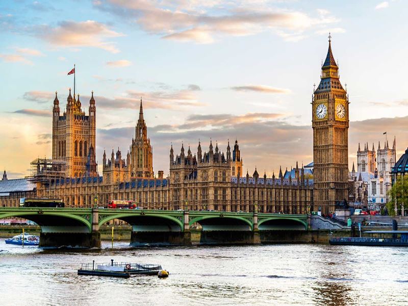 The Houses of Parliament loom behind Westminster Bridge on a fairly clear day, with the light reflecting off the Thames