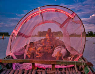 Shahidul Islam and Rowshan Ara, with their two daughters Sayma Khatun and Sumaiya Khatun under mosquito net on their boat. Photo: WFP/Sayed Asif Mahmud