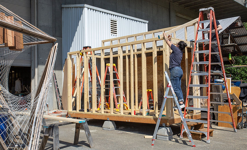 people on ladders building a shed