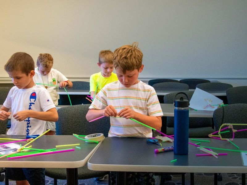 Four children practice arts and crafts inside a classroom.