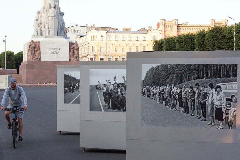 A cyclist passes the Freedom Monument during at a photo exhibition showing historical pictures of the Baltic Way human chain.