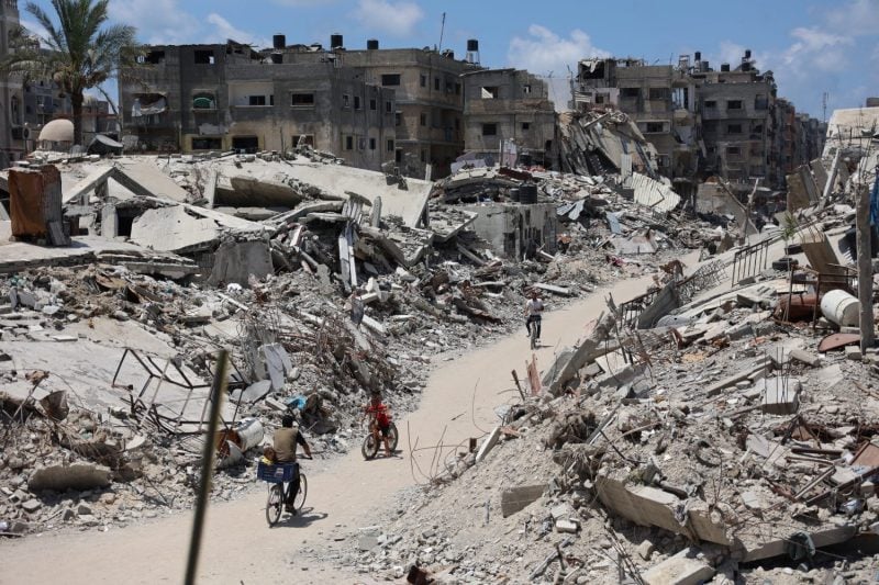 Palestinians ride past buildings leveled in previous Israeli military bombardments in northern Gaza on July 29.