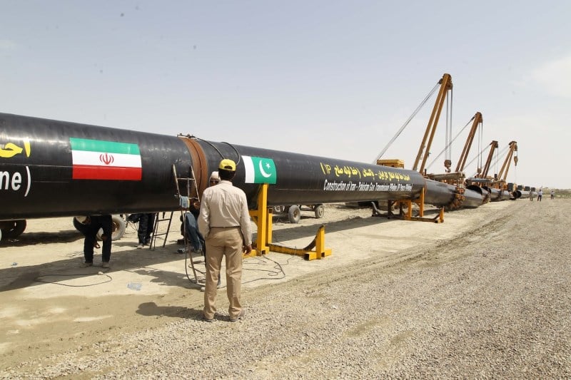 A worker stands in front of a section of a cross-border gas pipeline, in Chabahar, Iran.