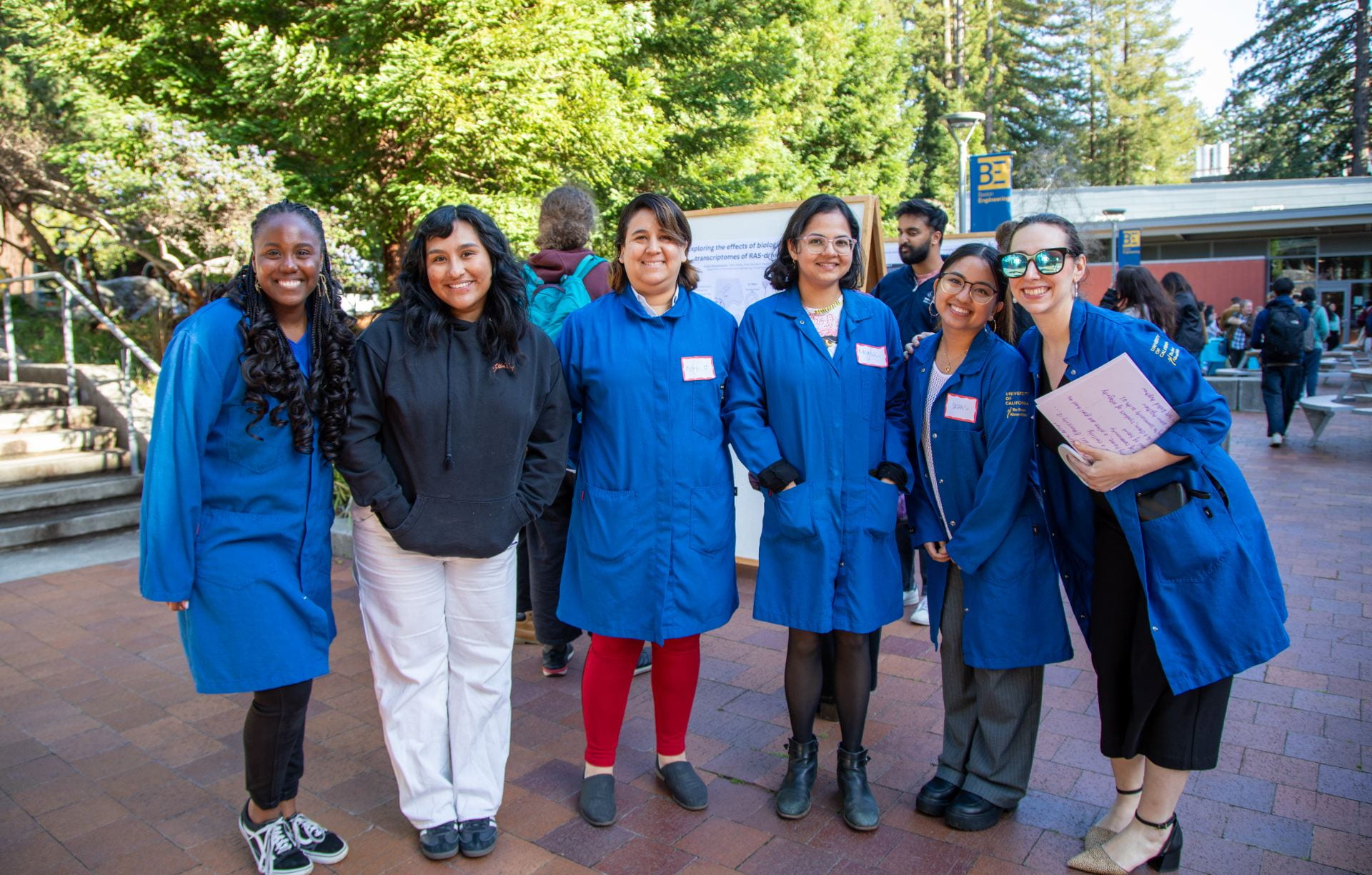 A group of smiling women in blue lab coats.