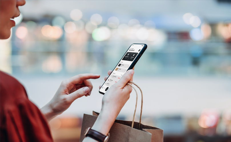 Woman with a shopping bag in her hand checking her phone