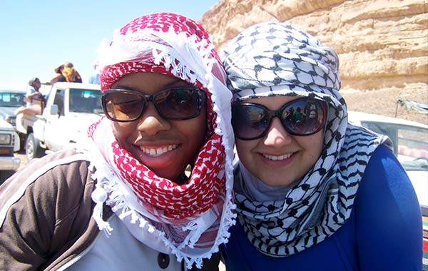 Two women in hijabs in an arid setting smiling