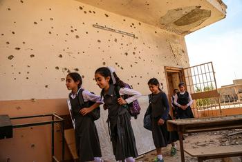 Schoolgirls in Anbar, Iraq, leave a classroom damaged by conflict.