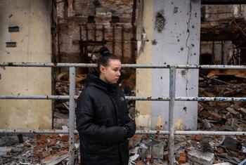 A young woman who survived a landmine explosion stands outside a bombed-out building in Izium, eastern Ukraine.