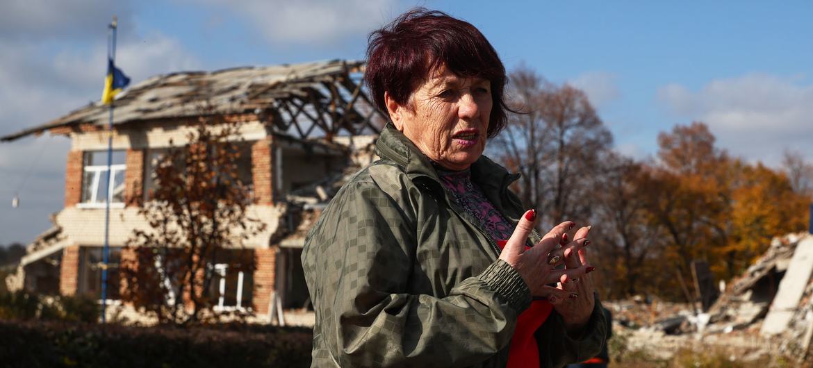 Mulher em frente a um prédio destruído em seu vilarejo em Zaporizka oblast, Ucrânia.