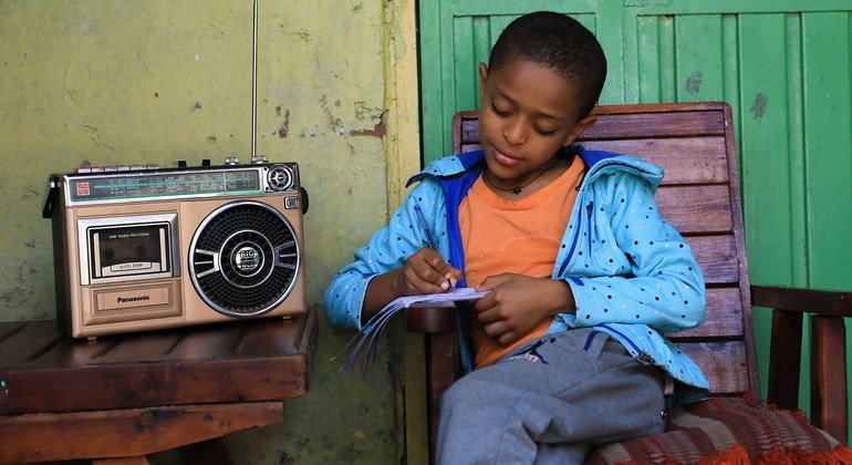 A young boy in Ethiopia attends class at home, taking lessons via the radio, which are being broadcast across the country. 