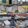 A twelve-year-old girl stands in front of her school in Kharkiv, Ukraine. It was destroyed in an air strike and she will now study online.